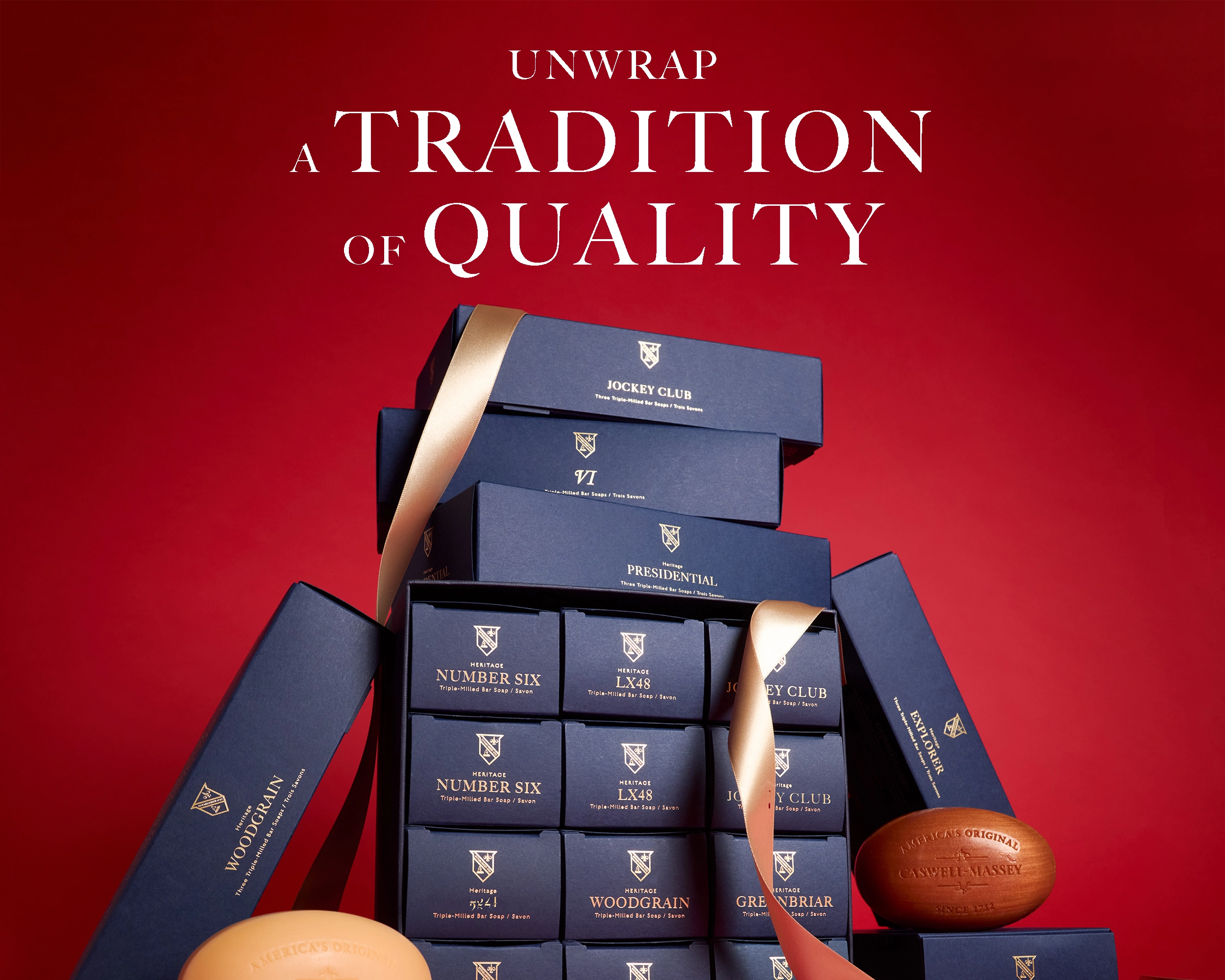 Caswell-Massey Gifts for Men: image shows men's soap sets and grooming gift sets in navy blue boxes stacked on top of one another wrapped in ribbon with bar soaps next to them.